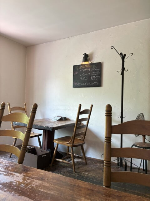 木製の椅子とテーブルが並ぶ店内、壁に黒板メニュー