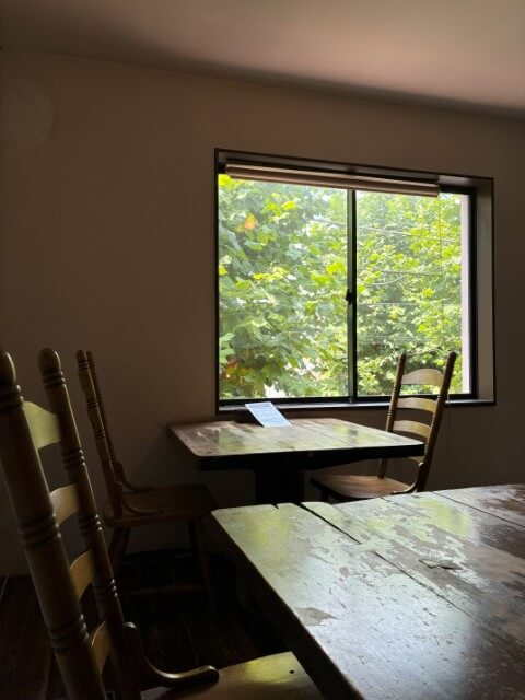 窓際に木製の椅子とテーブルが並ぶ静かな店内