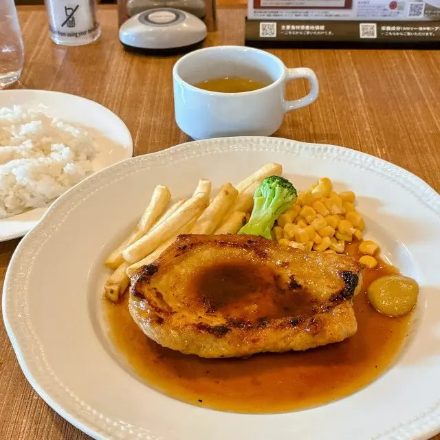 ソースがかかったポークソテーにフライドポテトとコーン、ライスとスープが付いたセット