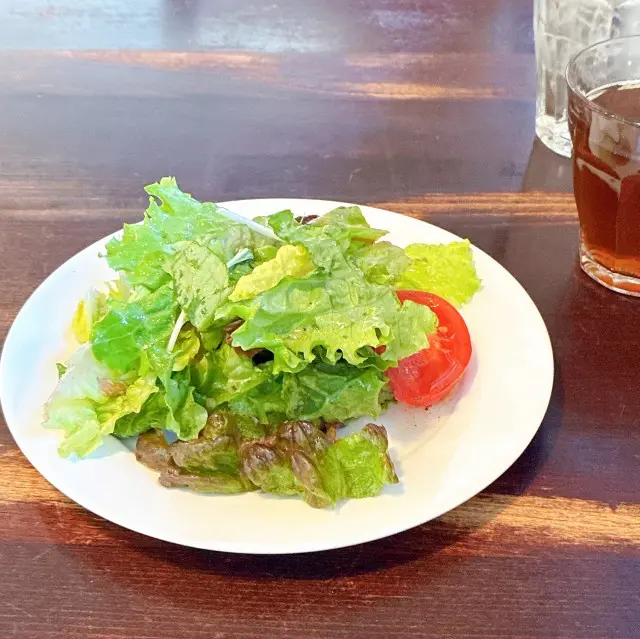 白い皿に盛り付けられた新鮮なサラダと、グラスに入ったセットのピーチティー