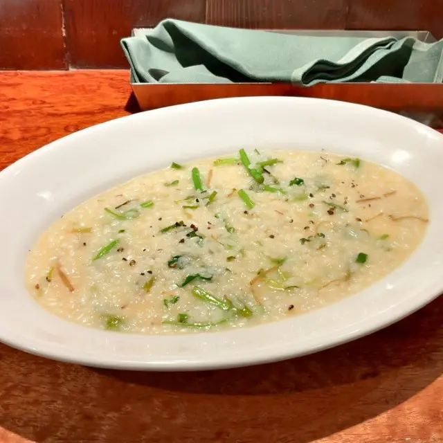 白いオーバル皿に盛り付けられた、刻んだセリが入ったクリーミーなリゾット