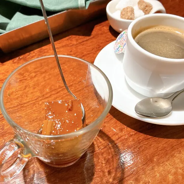 透明なカップに入ったカラメルプリンと、白いカップに注がれたホットコーヒー